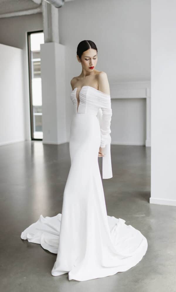 Tara LaTour McCartney: A modern stretch crepe fit-and-flare wedding dress with a plunging neckline and iconic back bow at Love and Lace Bridal Salon in Orange, CA