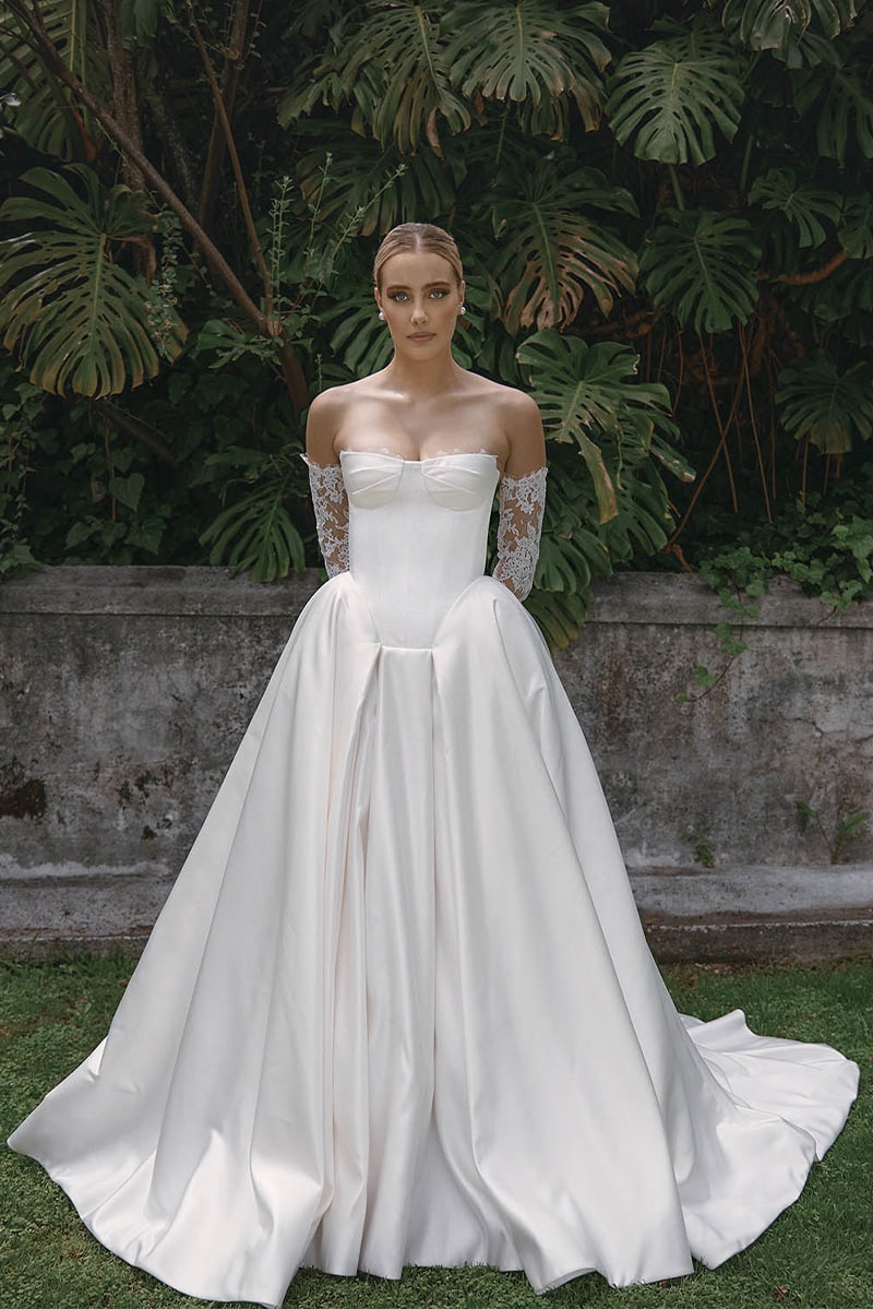 Kris wedding gown by Vagabond Bridal featuring sleek satin square basque silhouette with a corset-inspired bodice with delicate lace gloves, and voluminous box pleat skirt - available at Love and Lace Bridal OC.