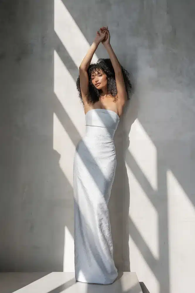 Elle by Alyssa Kristin Bridal, a strapless column wedding gown in sleek floral jacquard fabric with a modern silhouette at Love and Lace Bridal Salon in Orange, CA.