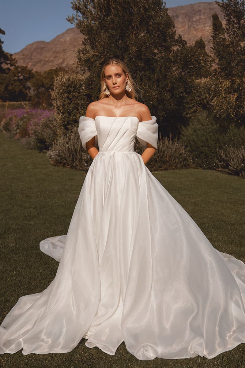 Calypso wedding dress by Vagabond Bridal featuring marshmallow organza, dramatic drapery, structured sleeves, and statement train at Love and Lace Bridal Orange County.