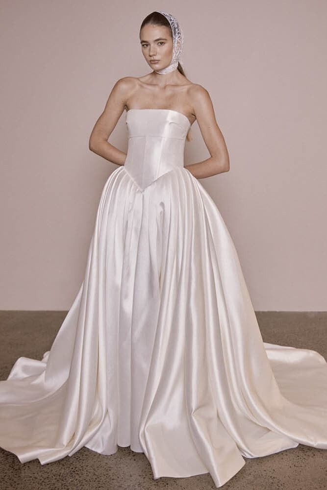 Victoire by Vagabond Bridal: A regal Mikado satin basque waist wedding dress featuring a structured corset bodice and a dramatic box pleat skirt at Love and Lace Bridal in Orange County