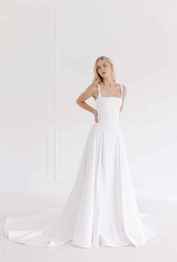 Tara LaTour Arabella: Modern drop waist bridal gown in matte satin with a unique arc bodice and pleated A-line skirt, available at Love and Lace Bridal Salon in Orange, CA