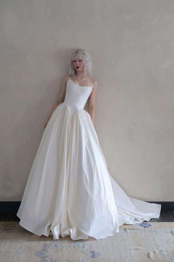 Hedy wedding dress by Tara LaTour featuring a structural strapless elongated basque waist bodice and full voluminous skirt, available at Love and Lace Bridal Salon in Orange, CA.