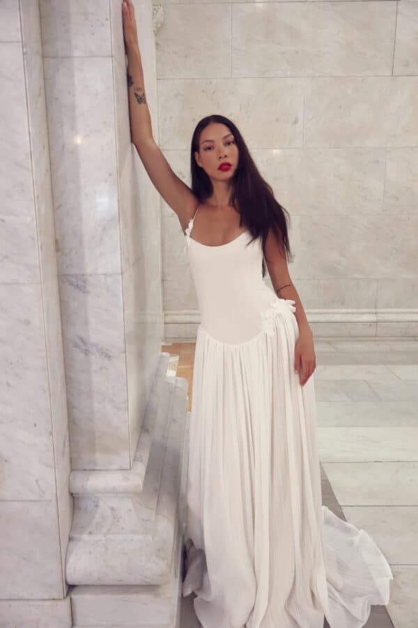 Cooper by Tara LaTour: A modern dropped arch drop waist wedding dress in pleated georgette over satin, featuring a scooping sweetheart neckline and handmade 3D fabric flowers available at Love and Lace Bridal Salon in Orange, CA.