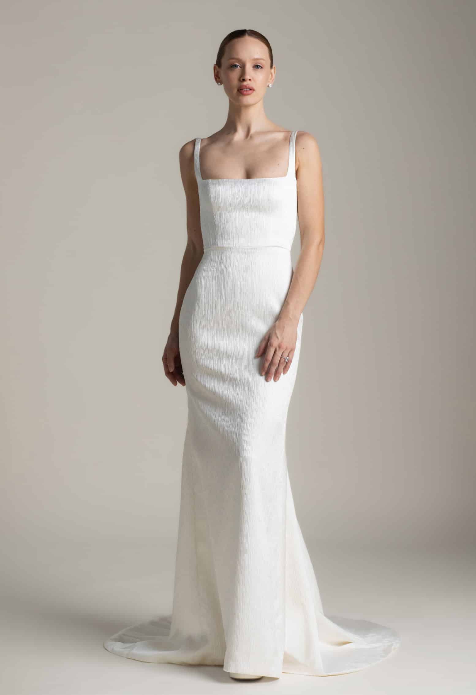 Daphne wedding dress by Aesling Bridal available at Love and Lace Bridal Salon in Orange, CA, featuring textured satin, a structured square neckline, 1/2-inch straps, long tie-back ribbons, and a 65-inch flared train.