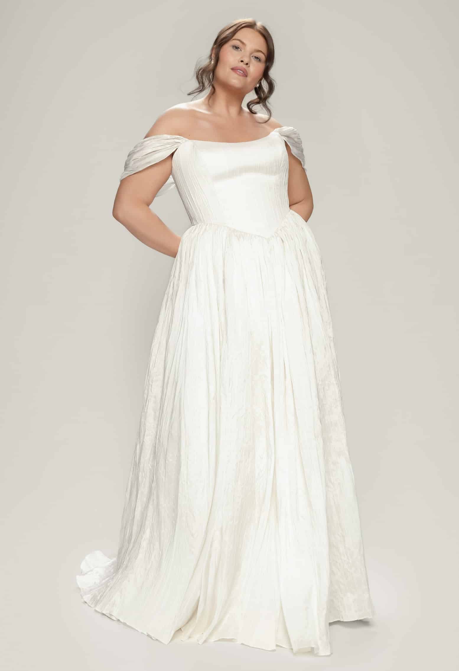 Hera plus size wedding dress by Aesling Bridal available at Love and Lace Bridal Salon in Orange, CA, featuring crisp pleated taffeta, a strapless scoop cat-eye bodice, an elongated structural basque waist, a full gathered circle skirt, and a 65-inch train.