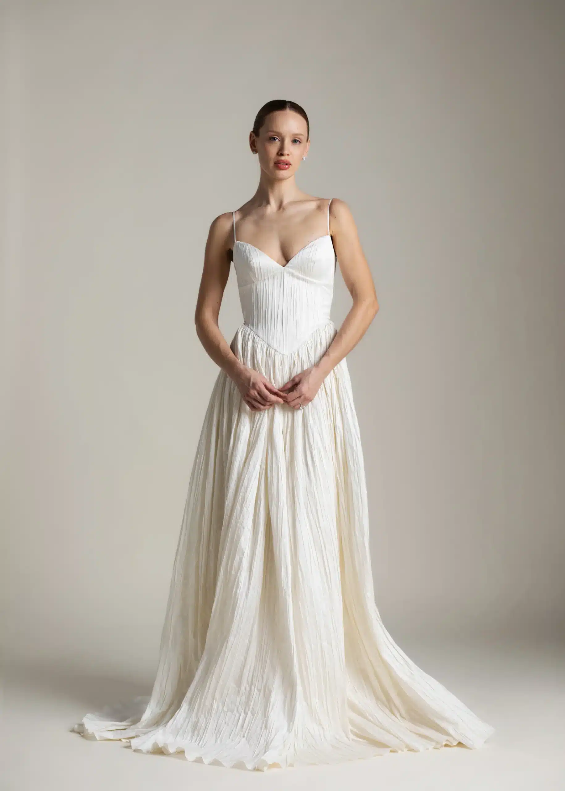 Rhea wedding dress by Aesling Bridal available at Love and Lace Bridal Salon in Orange, CA, featuring crisp pleated taffeta, a plunging V-neckline with delicate 1/2-inch straps, an exaggerated basque waist, a full gathered circle skirt, and a 65-inch train.